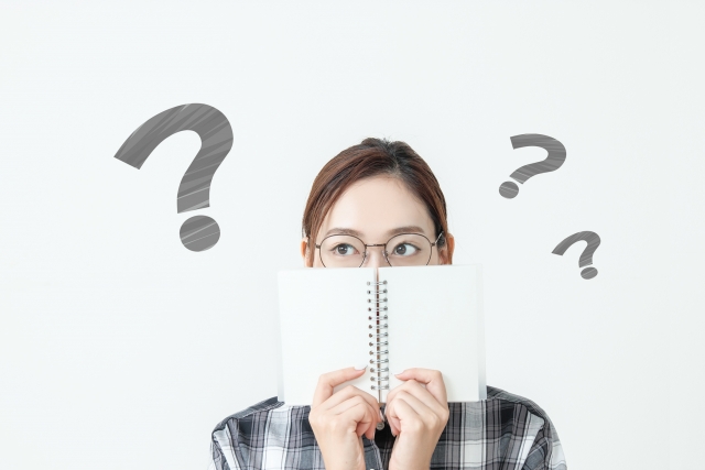 ノートで口元を隠す眼鏡姿の女性