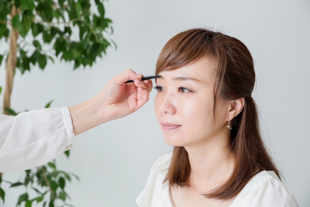 眉をメイクしてもらう女性