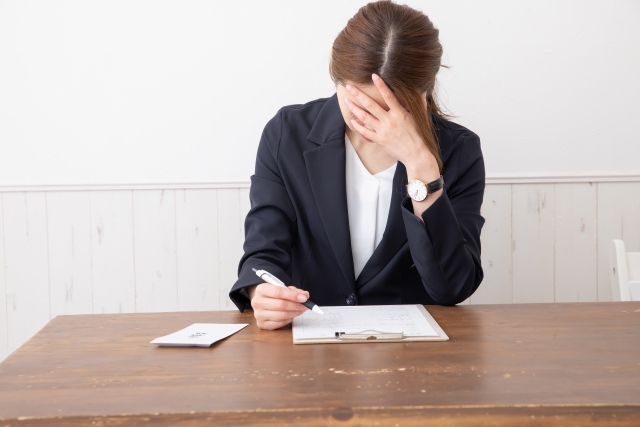書類を見て額に手を当てる女性