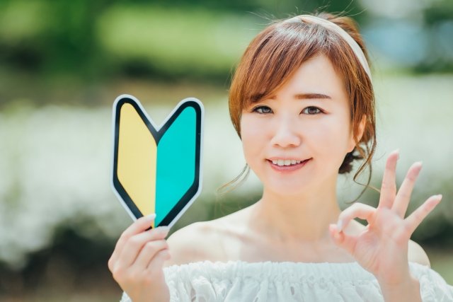 初心者マークを手にOKサインを出す女性